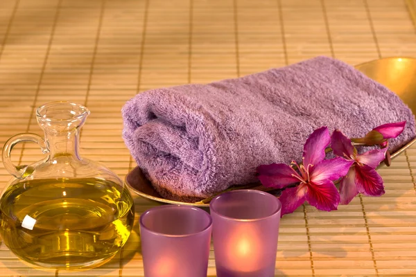 Essential oil, candles, towel and purple flowers. — Stock Photo, Image