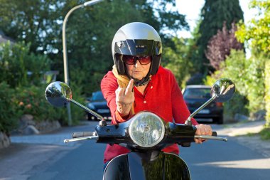yaşlı kadın kaba bir jest yaparak bir scooter üzerinde