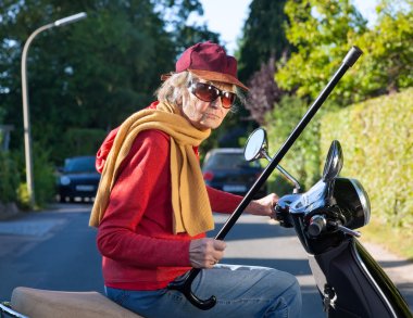 Bir scooter üzerinde kötü temperli yaşlı kadın