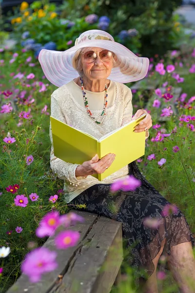 Elegante señora mayor leyendo en el jardín — Foto de Stock