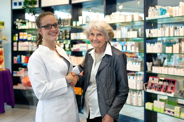 Старша леді тремтить руками з молодою жінкою-фармацевтом — стокове фото