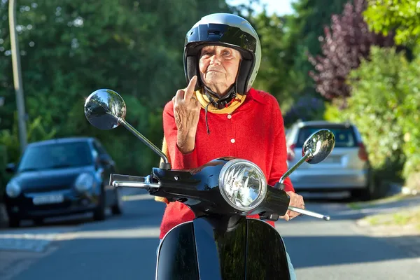Angry old lady on a scooter making a rude gesture — Stock Photo, Image