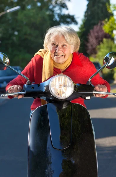 Směje se starší žena nepřiměřená rychlost na kole skútru — Stock fotografie