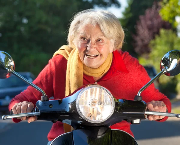Senior mulher excesso de velocidade em uma moto scooter — Fotografia de Stock