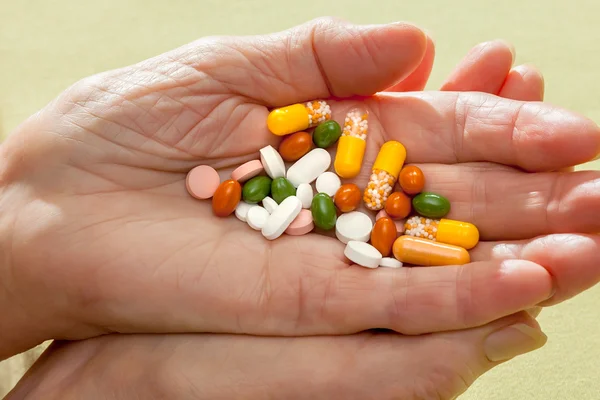 Kapslar och tabletter i en öppen handflata — Stockfoto