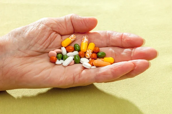 Comprimidos, pastillas y cápsulas en la mano extendida —  Fotos de Stock