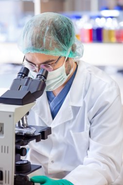 bilim adamı bir laboratuarda mikroskop bakıyor. 