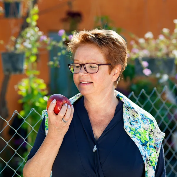 Mujer mayor sana comiendo una manzana roja . — Foto de Stock