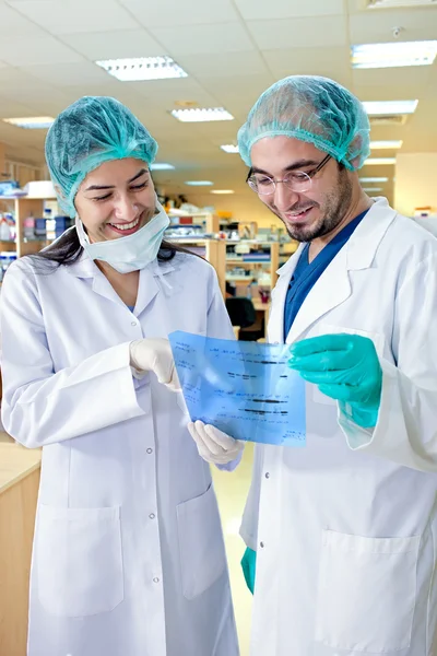 Labortechniker lächeln, während sie die Ergebnisse studieren. — Stockfoto