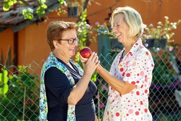 Skrattar äldre kvinnor med ett rött äpple. — Stockfoto