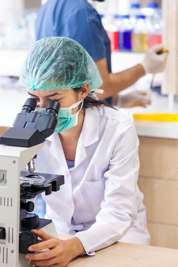 Female lab technician sitting at a microscope. 