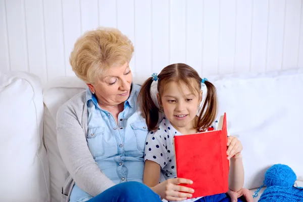 Avó e menina ler livro feliz juntos em casa — Fotografia de Stock