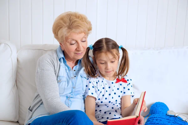 Grandmother and little girl reading book happy together at home — Stock Photo, Image