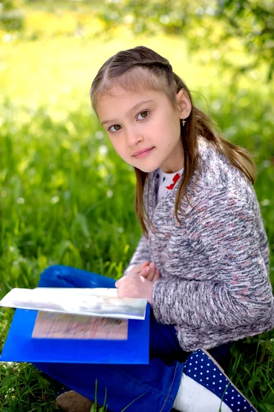 Außenporträt eines niedlichen jungen Mädchens beim Lesen eines Buches — Stockfoto