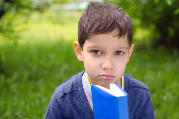 本を読んで、かわいい若い男の子の屋外のポートレート — ストック写真
