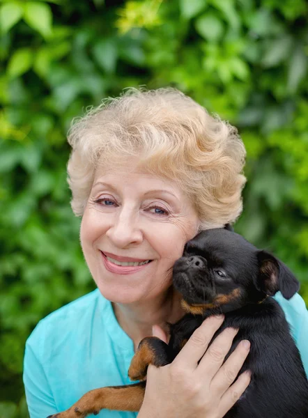 Hermosa mujer mayor sonriente con perro pequeño en el parque de verano Imagen De Stock