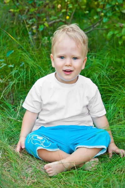 草の上に座ってあぐらの小さな男の子 — ストック写真