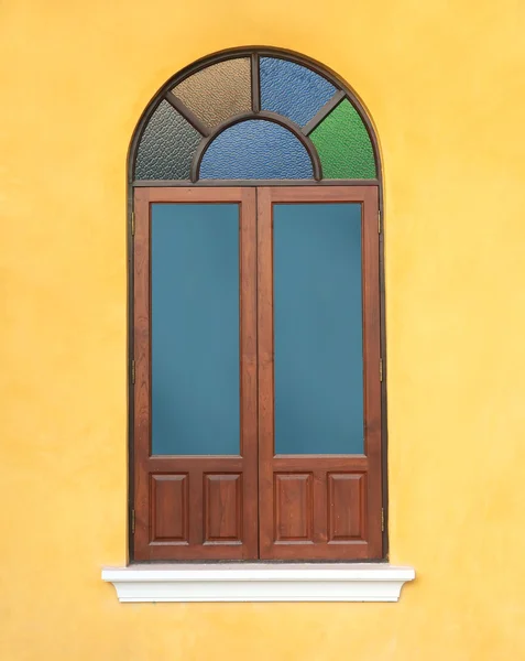 Holzfenster mit buntem Glas an gelber Wand — Stockfoto