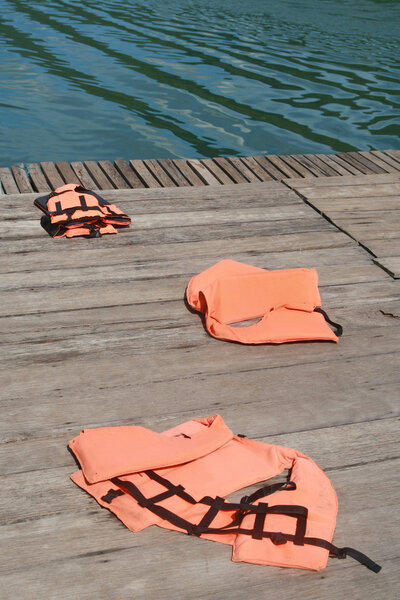 Life vest on wood floor with a boat on river background