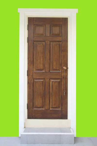 Drzwi z drewna brązowego z zieloną ścianą — Zdjęcie stockowe