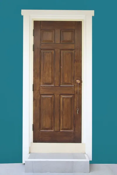 Drzwi z drewna brązowego z zieloną ścianą — Zdjęcie stockowe