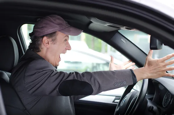 Angry upset man at wheel driving his car screaming — Stock Photo, Image