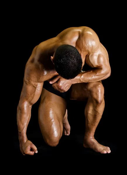 Bodybuilder kneeling with head down — Stock Photo, Image