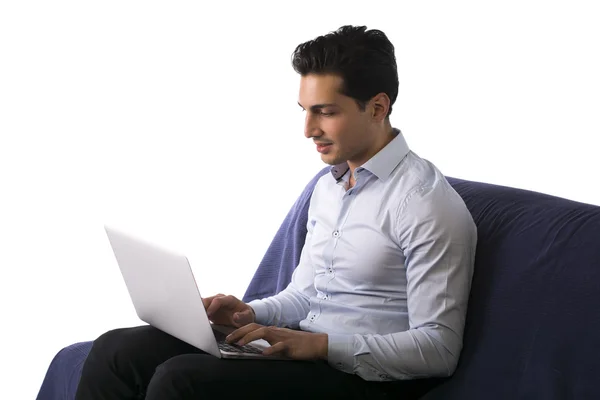 Hombre joven que trabaja en el ordenador portátil mientras está sentado en el sofá —  Fotos de Stock