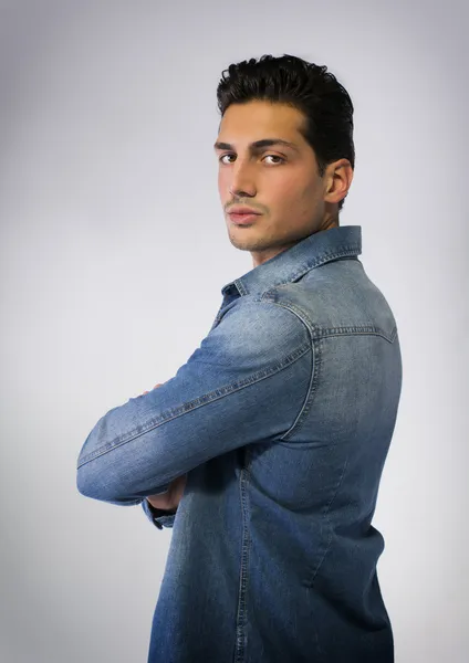 Young man wearing denim shirt, arms crossed on chest — Stock Photo, Image