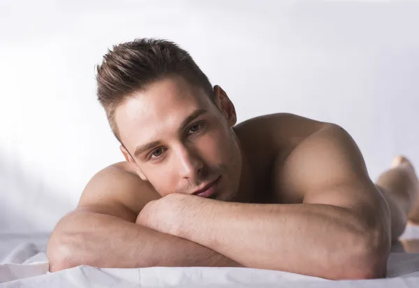 Cute expression, naked young man on white sheets — Stock Photo, Image