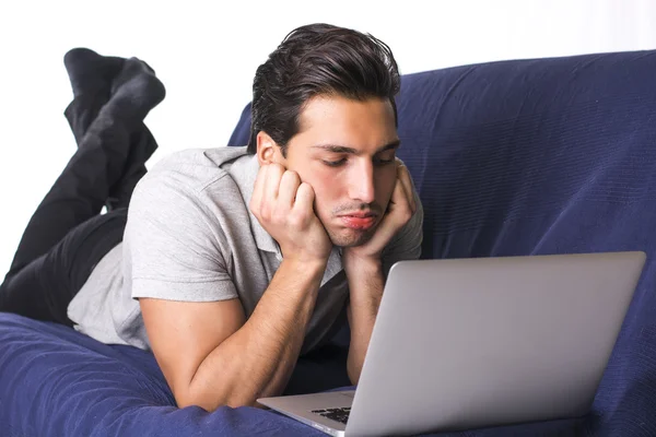 Jovem decepcionado ou entediado olhando para o laptop PC — Fotografia de Stock