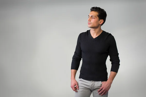 Красивий латинський молодий чоловік стоїть на сірому фоні . — стокове фото
