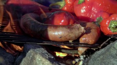 Taze kesilmiş karışık sebzeler ve sosisler açık havada mangal kömürü ızgarasında kızartılıyor. Yavaş çekim