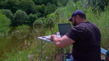 Graphic designer with laptop working with laptop and graphic tablet outdoor