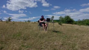 Man with laptop sitting and networking in the country