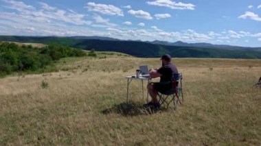 Man with laptop sitting and networking in the country