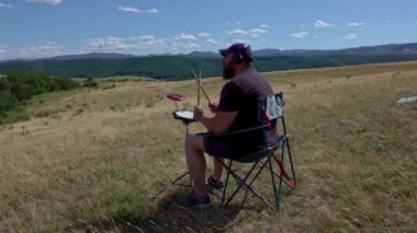 Artist with practice pads and headsets in summer meadow