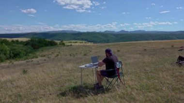 Graphic designer with laptop working with laptop and graphic tablet outdoor