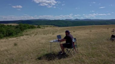 Graphic designer with laptop working with laptop and graphic tablet outdoor