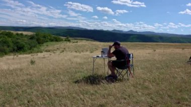 Man with laptop sitting and networking in the country