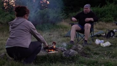 Hikers preparing food at campfire at dawn