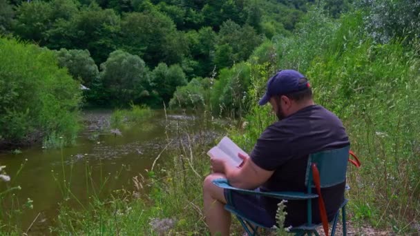 Man Relax Read Books Outdoor Lake — Vídeo de stock