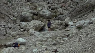 Hiker woman in a rocky valley with spring stream water in the mountain river