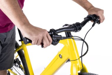 Tanımlanamayan erkek elleri bisikletin gidonunu tutuyor, beyaz arka planda izole edilmiş, yakın plan görüntüsü var..