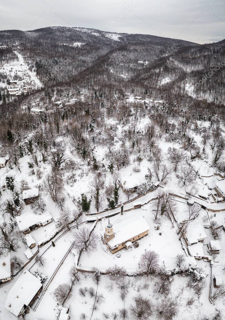 Amazing aerial view of calm winter morning with snow falling over the old beautiful houses in the revival architectural complex Bozhenci, Bulgaria.