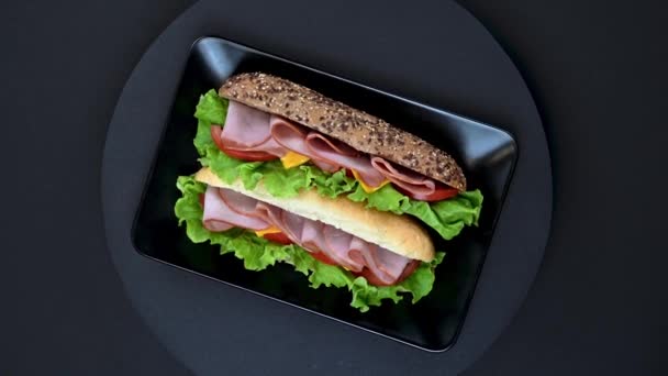 带有火腿 融化的奶酪和蔬菜的美味三明治在深色背景下旋转的视频 — 图库视频影像