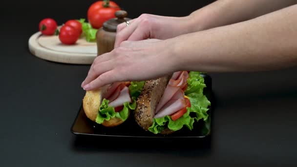 女性の手でビデオ黒プレートでハム チーズ 野菜とおいしいサンドイッチを準備 — ストック動画