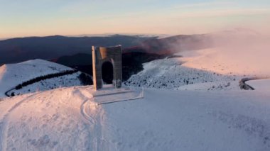 Bulgaristan 'ın Beklemeto geçidinde, Balkan Dağları' nın ana sırtında, karla kaplı dağ yamaçları ve Özgürlük Anıtı 'nın yer aldığı manzara videosu gün doğumunda Bulgaristan' ın Beklemeto geçidi