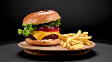 Lezzetli ev yapımı sığır burger ve taze malzemeler küçük ahşap kesme tahtasında servis ediliyor. Koyu arka planda patates kızartması dönüyor. Yakın plan görüş.