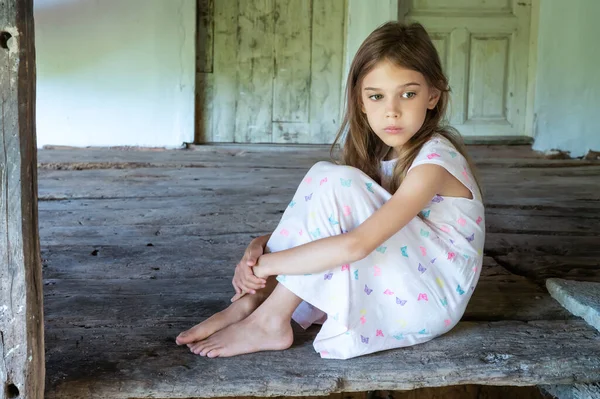 Ahşap zemini olan eski bir kır evinin terasında çıplak ayaklı güzel bir kızın klasik portresi.
